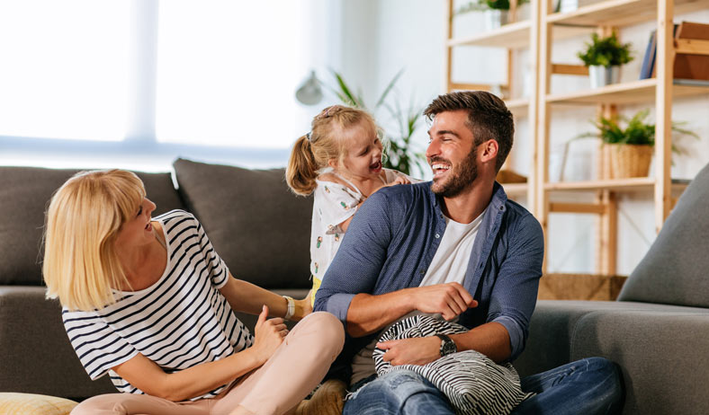 Family playing on the floor next to a couch